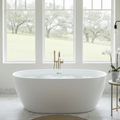 Freestanding oval soaking bathtub in matte white, centered in a bright modern farmhouse bathroom with marble tile floors